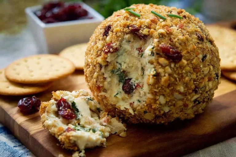 Cranberry Rosemary Vegan Cheese Ball garnished with herbs on a serving platter