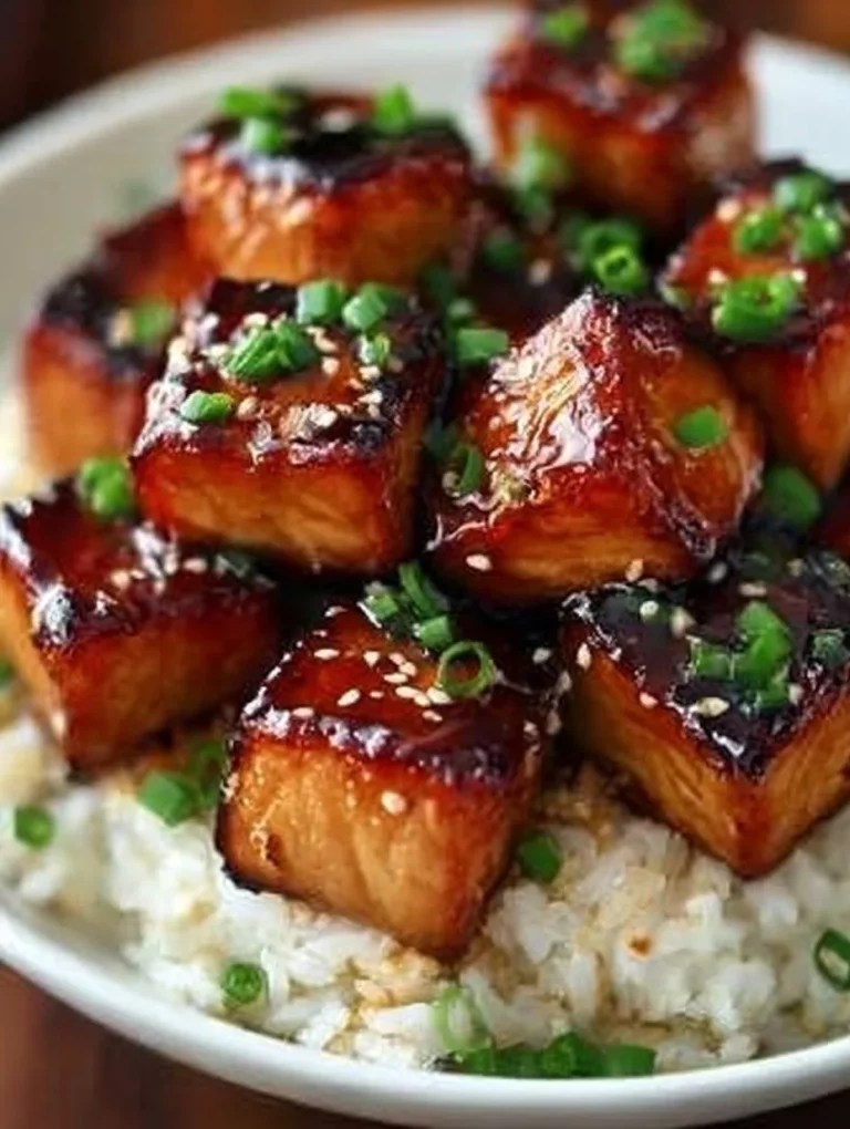Sticky honey garlic salmon bites on a plate with garnishes