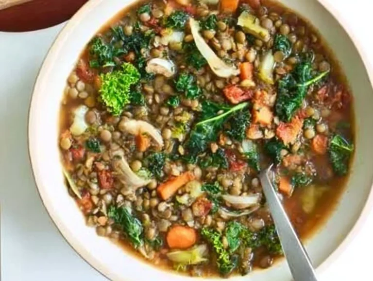 Bowl of easy lentil vegetable soup garnished with fresh parsley on a wooden table.