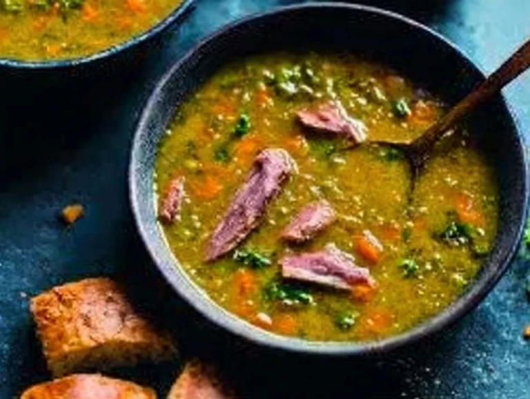 Bowl of traditional split pea soup garnished with parsley and bread