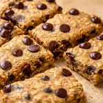 Naturally sweetened banana tahini breakfast bars on a wooden plate with bananas and tahini