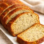 Flourless Banana Yogurt Cake topped with fresh bananas and yogurt on a white plate.