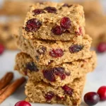 Homemade cranberry oatmeal bars with a golden brown top and cranberries visible